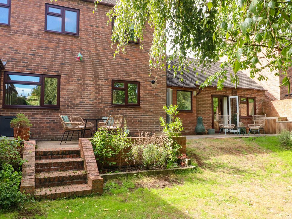 A backyard with a brick building and patio area at 7 Forge Close