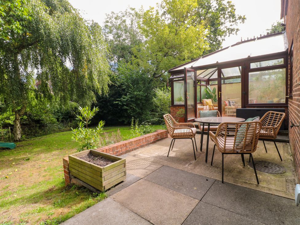 A garden with a seating area in front of a conservatory at 7 Forge Close