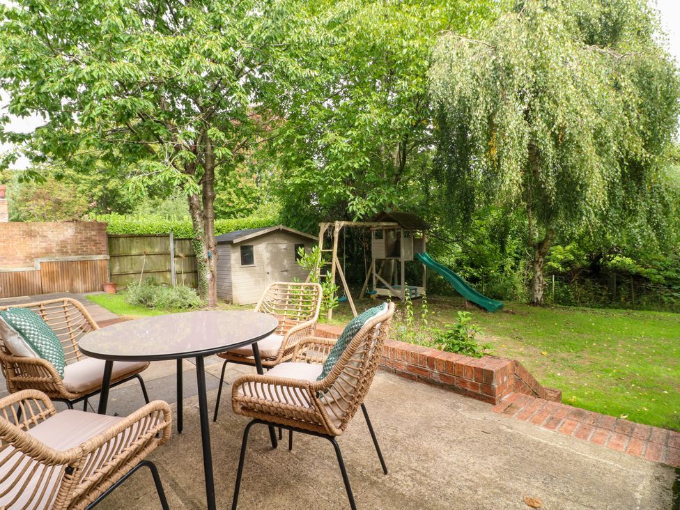 A garden with a table and chairs, a playhouse, and a slide at 7 Forge Close
