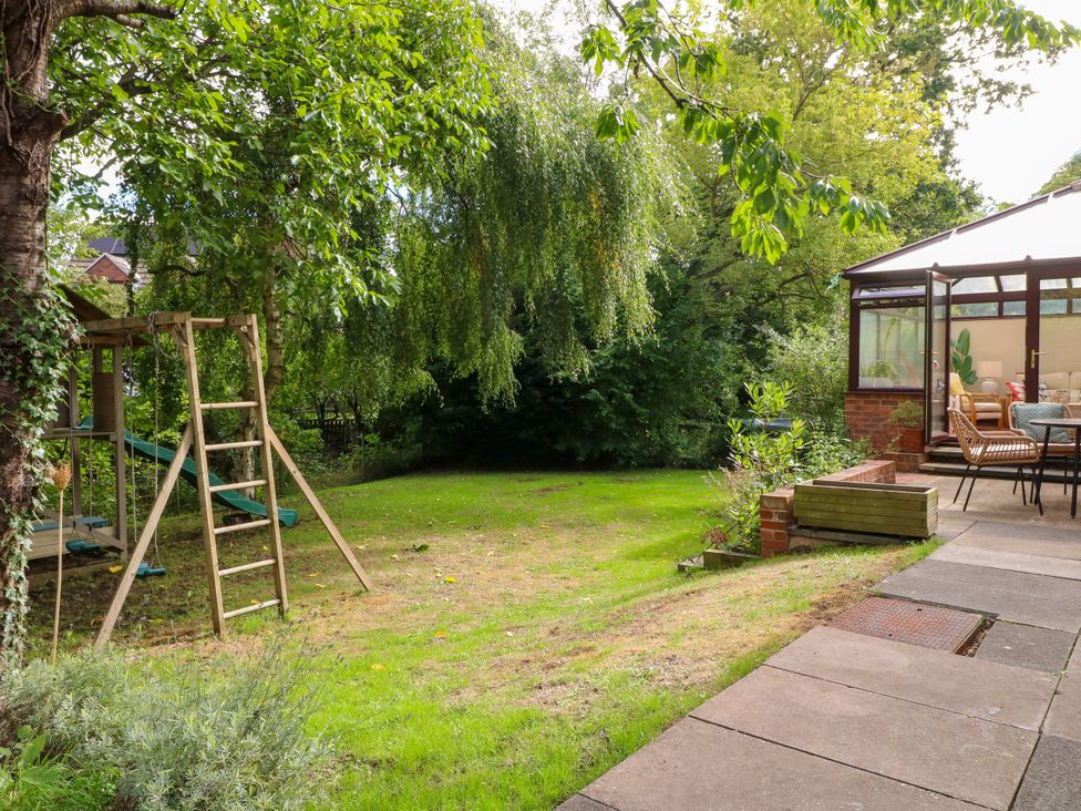 A garden with a play structure and patio seating at 7 Forge Close