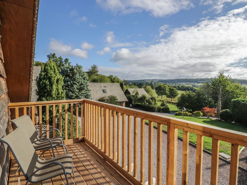 A balcony with chairs overlooking fields and trees at Chestnut Lodge in Worcester