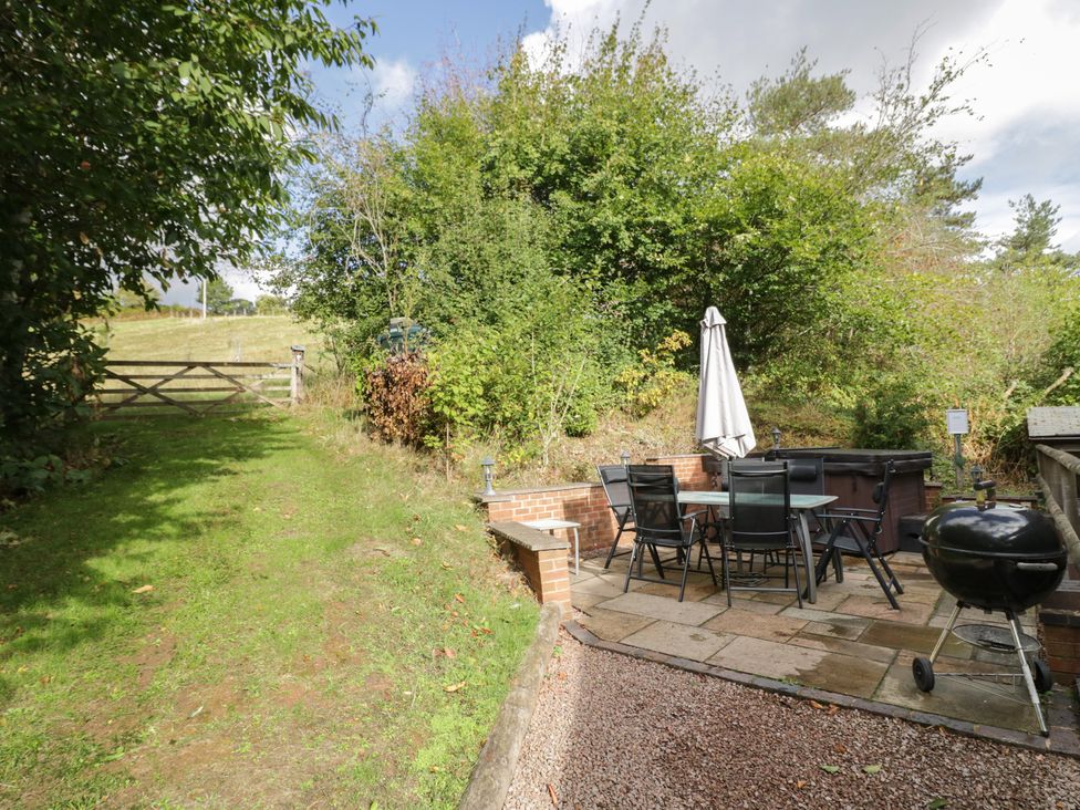 An outdoor garden with a table and chairs near a hot tub at Chestnut Lodge in Worcester