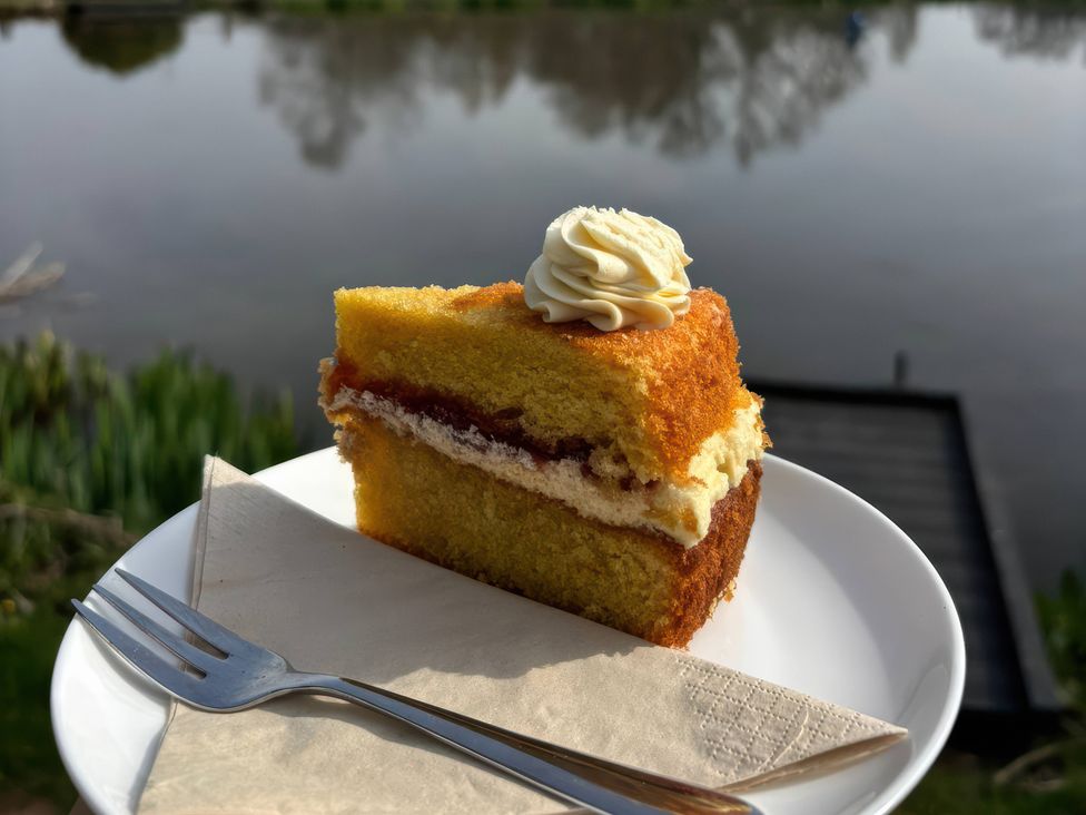 A piece of cake on a plate by a water body at Kingfisher in Worcester