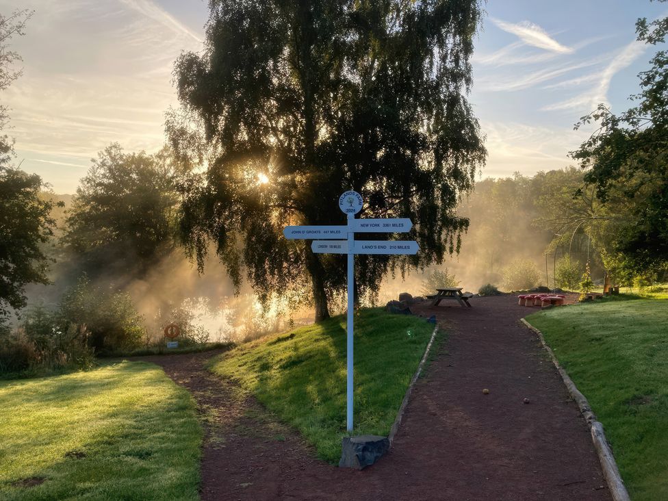 A path with a signpost and trees near a river at Kingfisher in Worcester