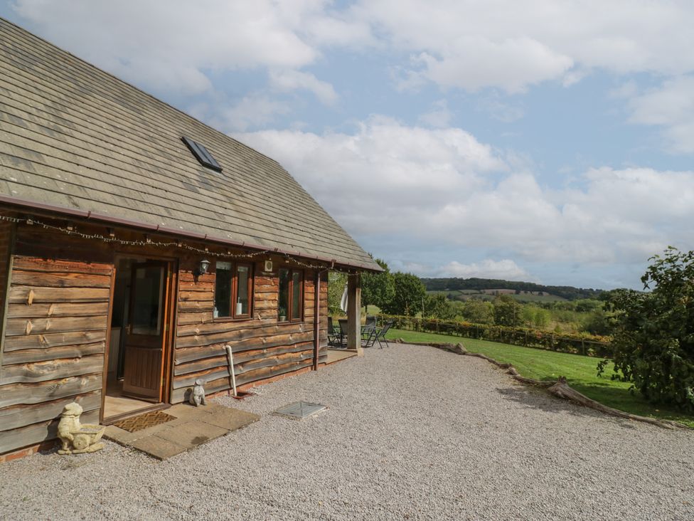 A wooden house with a gravel area and chairs at Kingfisher in Worcester