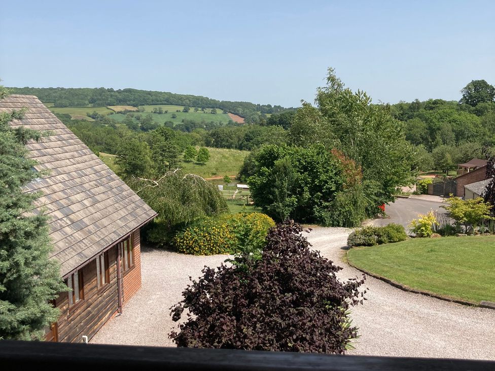 A view of a house and garden with trees and hills at Woodpecker Worcestershire