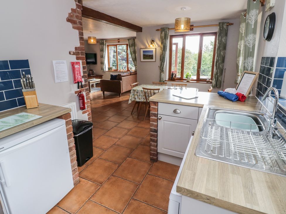 A kitchen with countertop, fridge, and seating area at Woodpecker in Worcester
