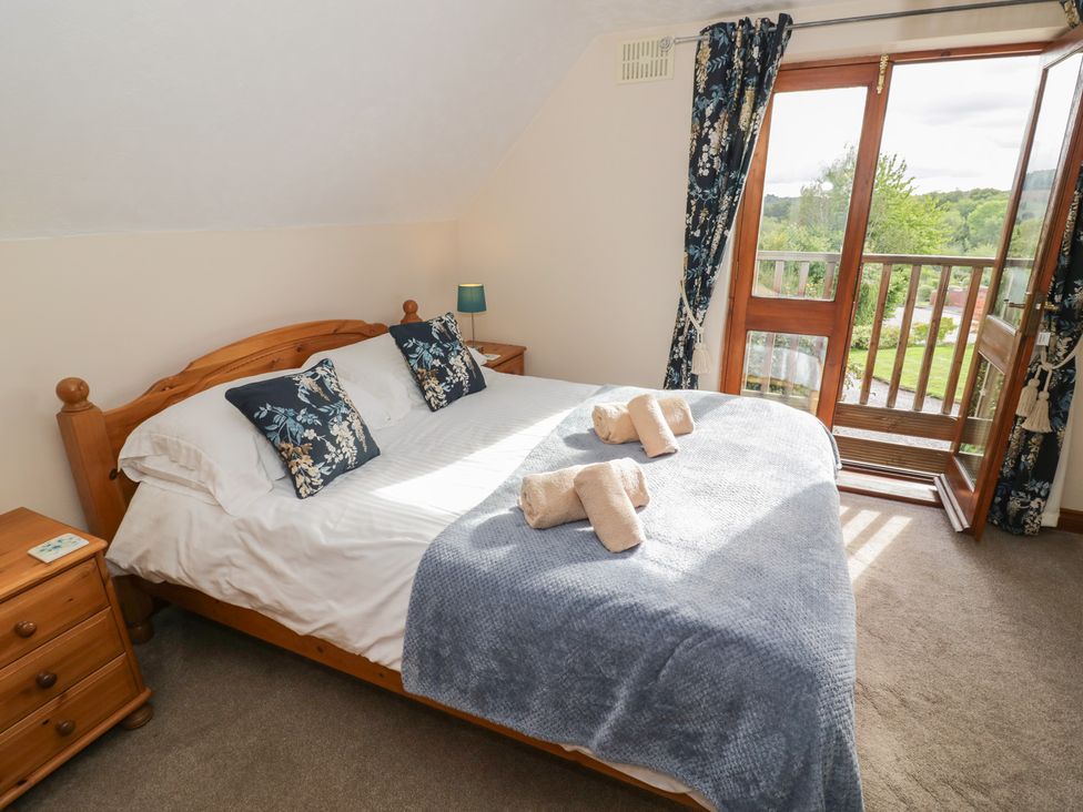 A bedroom with a bed and balcony door at Woodpecker in Worcester