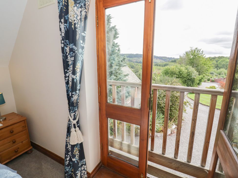 A bedroom with a balcony door and a wooden bedside table at Woodpecker in Worcester