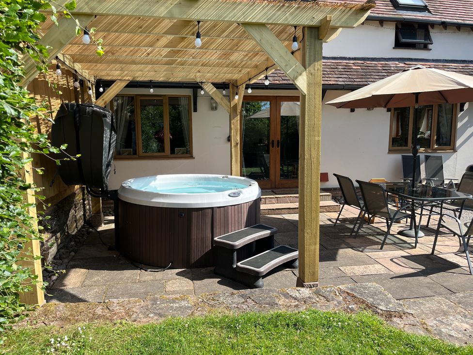 An outdoor area with a hot tub and dining set at Chaff House in Worcester