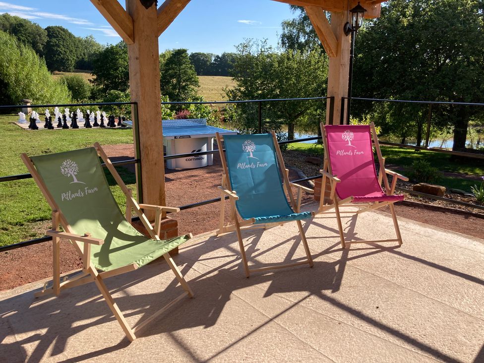 Three deck chairs with a view of chess pieces and trees at Pitlands Farm in Worcester