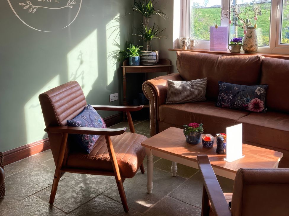 A snug with a brown couch and a wooden table at Chaff House in Worcester
