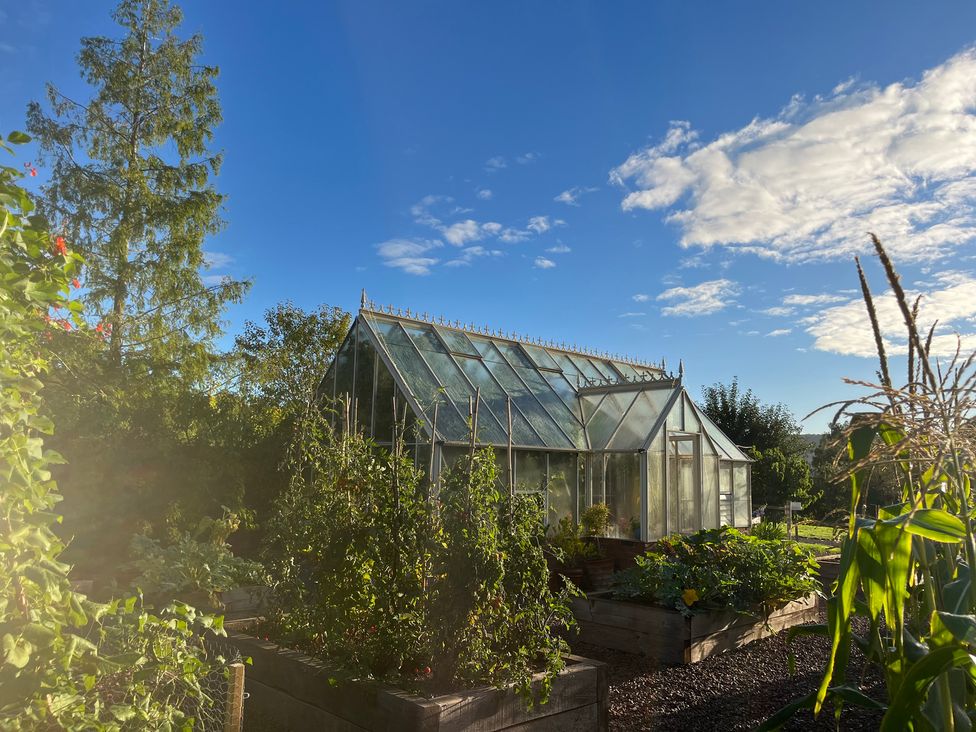 A greenhouse surrounded by vegetable beds in a garden at Chaff House in Worcester