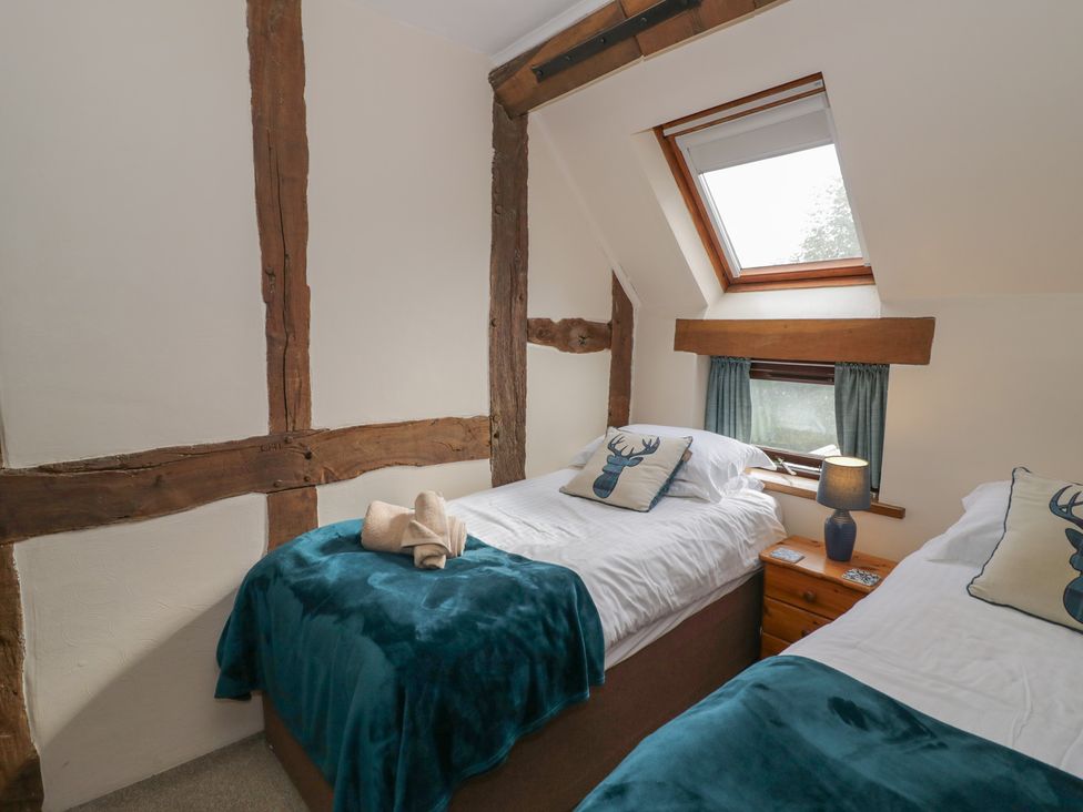 A bedroom with two beds, a lamp and a window at Chaff House in Worcester