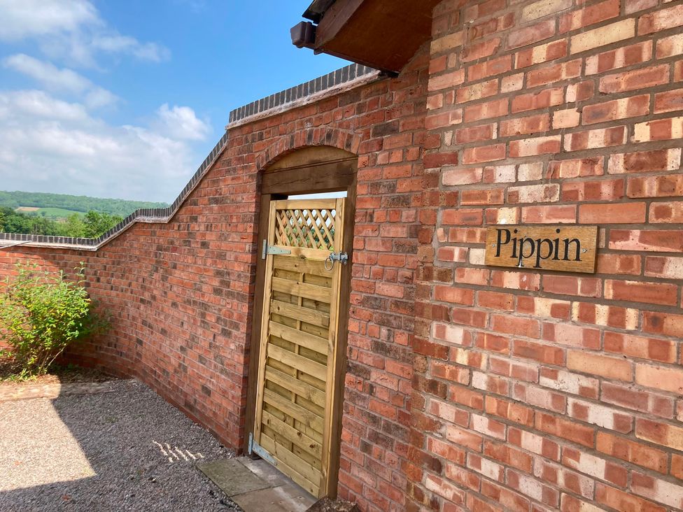 An outdoor entrance with a wooden gate and brick wall at Pippin in Worcester