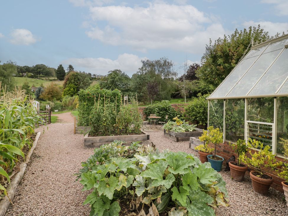 A garden with a greenhouse and vegetable beds at Bramley in Worcester