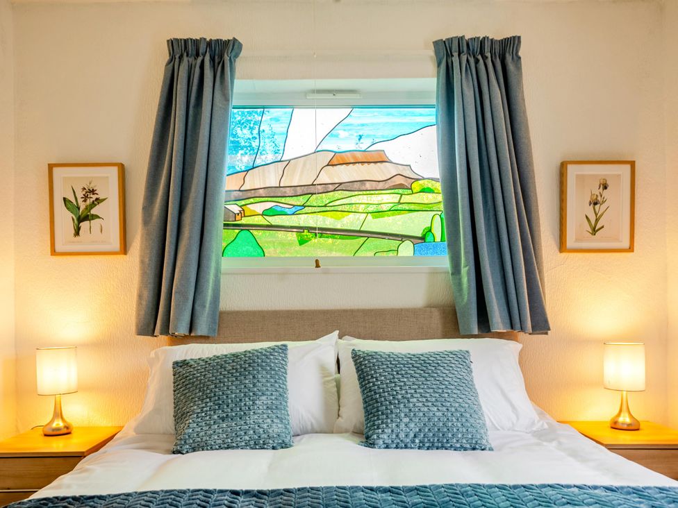 A bedroom with a bed and stained glass window at Waltergarth in Horton-In-Ribblesdale
