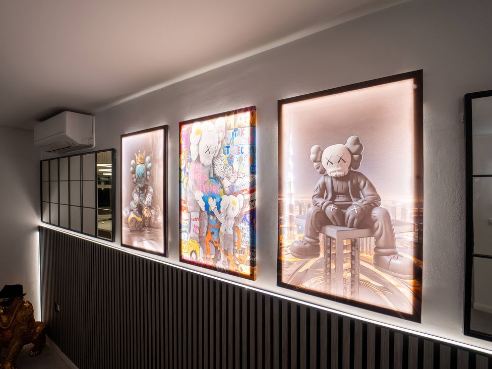A wall with framed artworks and a mirror at 29 Batchworth Lane in Northwood, Hertfordshire