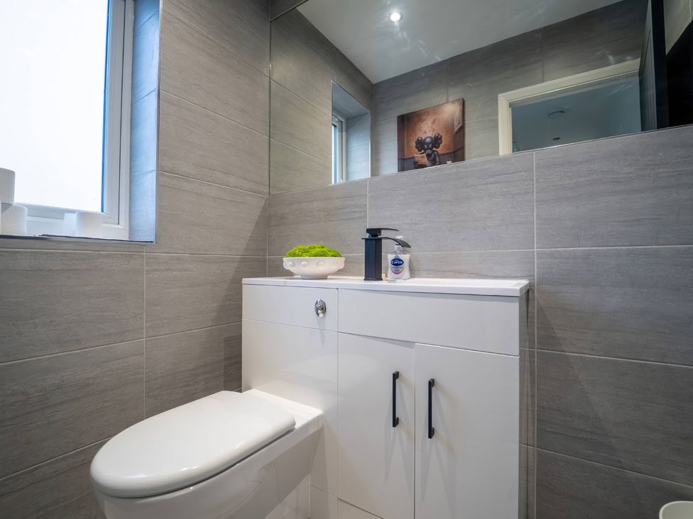 A bathroom with a toilet, sink, and window at 29 Batchworth Lane Northwood, Hertfordshire
