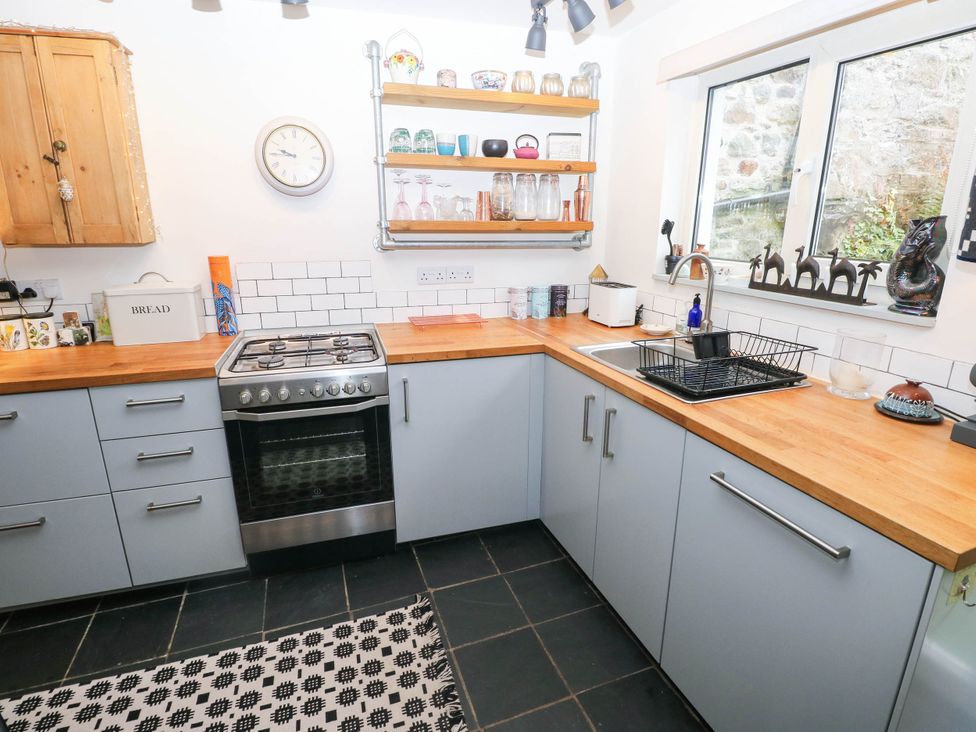 A kitchen with a stove and shelving at 11 Church Street Narberth