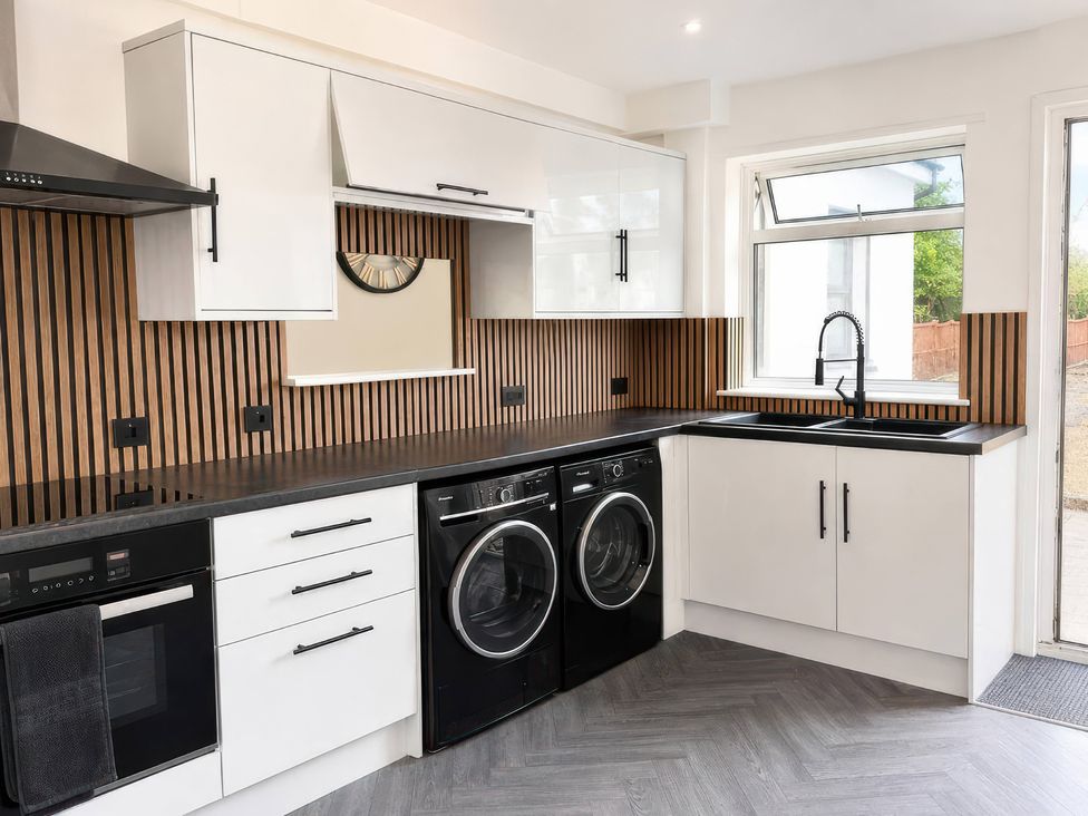 A kitchen with a washing machine and dryer at 35 Vivian Gardens in Watford