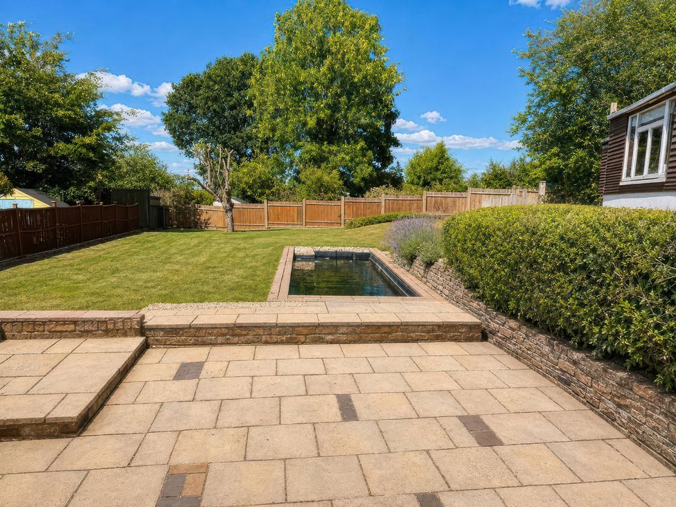 A garden with a swimming pool and stone patio at 35 Vivian Gardens Watford