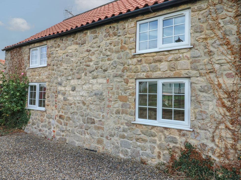An exterior view of a stone cottage with windows at Millstone Cottage in Ripon