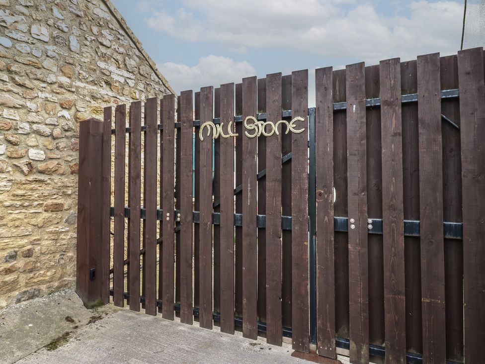 A wooden gate with a sign at Millstone Cottage in Ripon