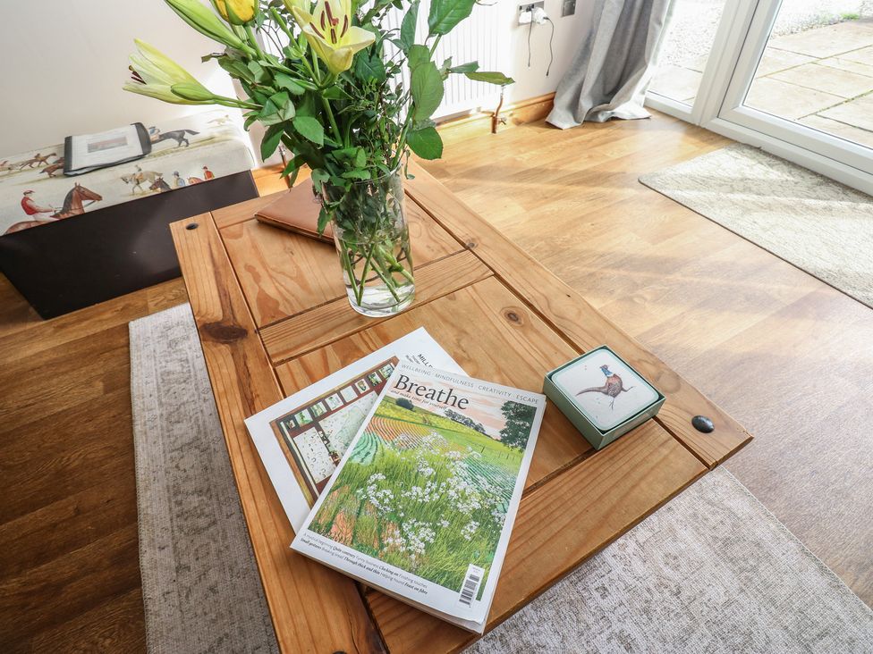 A coffee table with a vase of flowers and magazines at Millstone Cottage in Ripon
