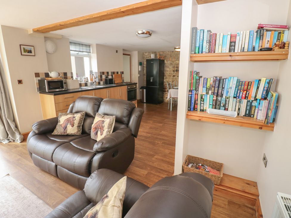 A living room with a sofa and bookshelf at Millstone Cottage in Ripon