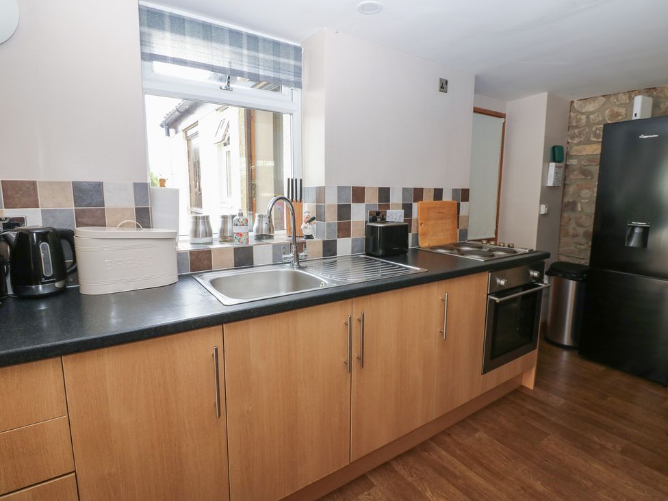 A kitchen with wooden cabinets and appliances at Millstone Cottage in Ripon