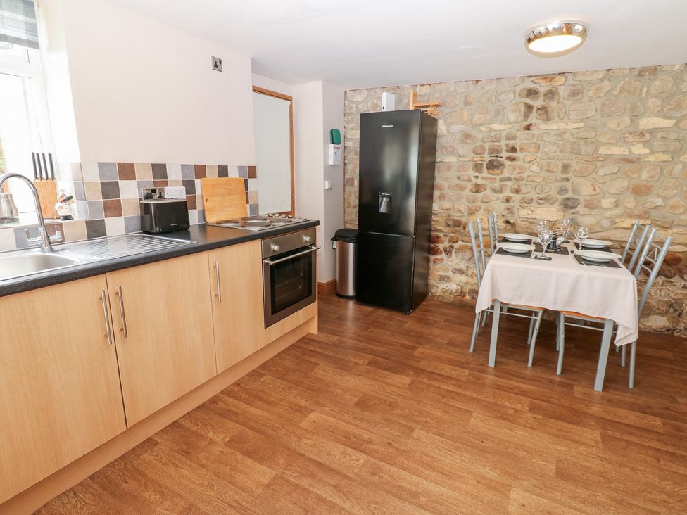 A kitchen with appliances and a dining area at Millstone Cottage Ripon