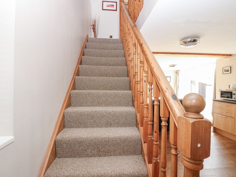 Stairs with wooden banister leading up to a doorway at Millstone Cottage in Ripon