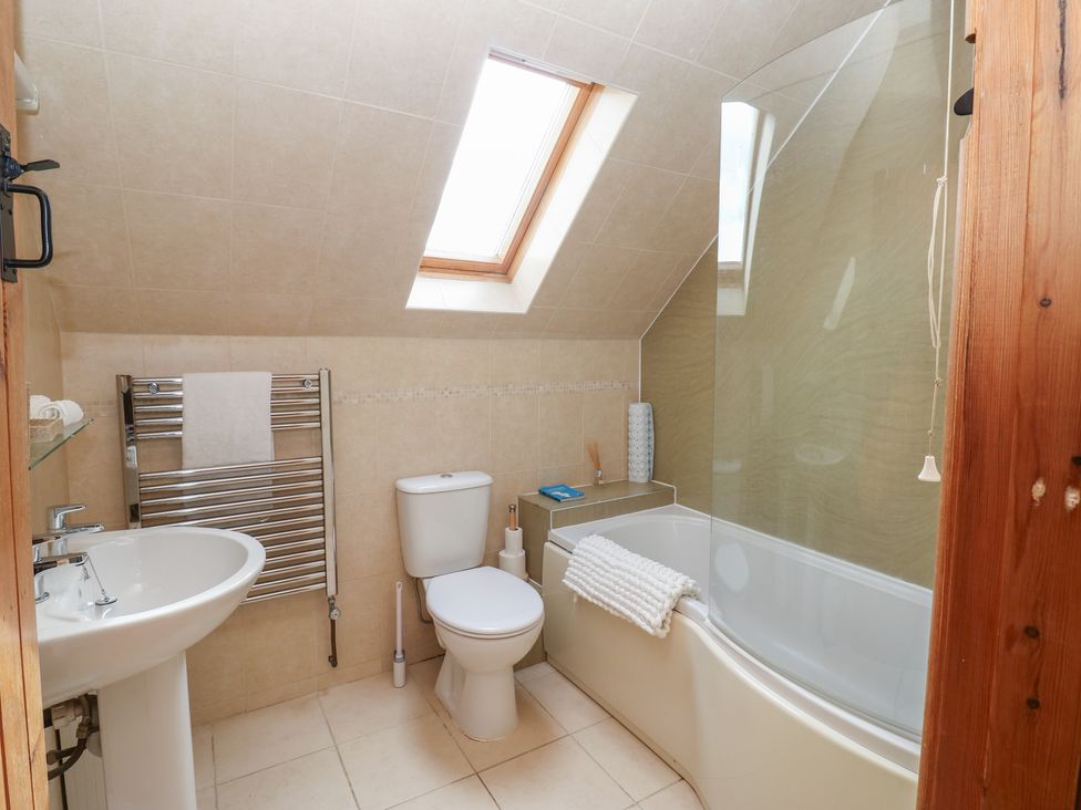 A bathroom featuring a bathtub, toilet, and sink at Millstone Cottage in Ripon