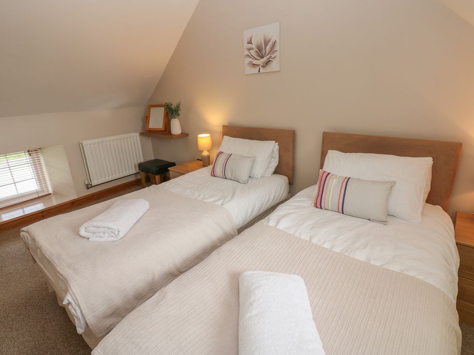A bedroom with twin beds and a bedside table at Millstone Cottage in Ripon
