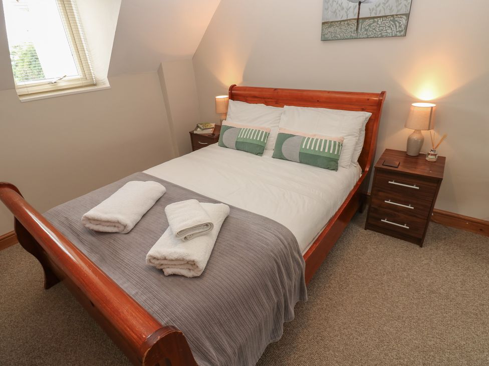A bedroom with a bed and nightstand at Millstone Cottage in Ripon