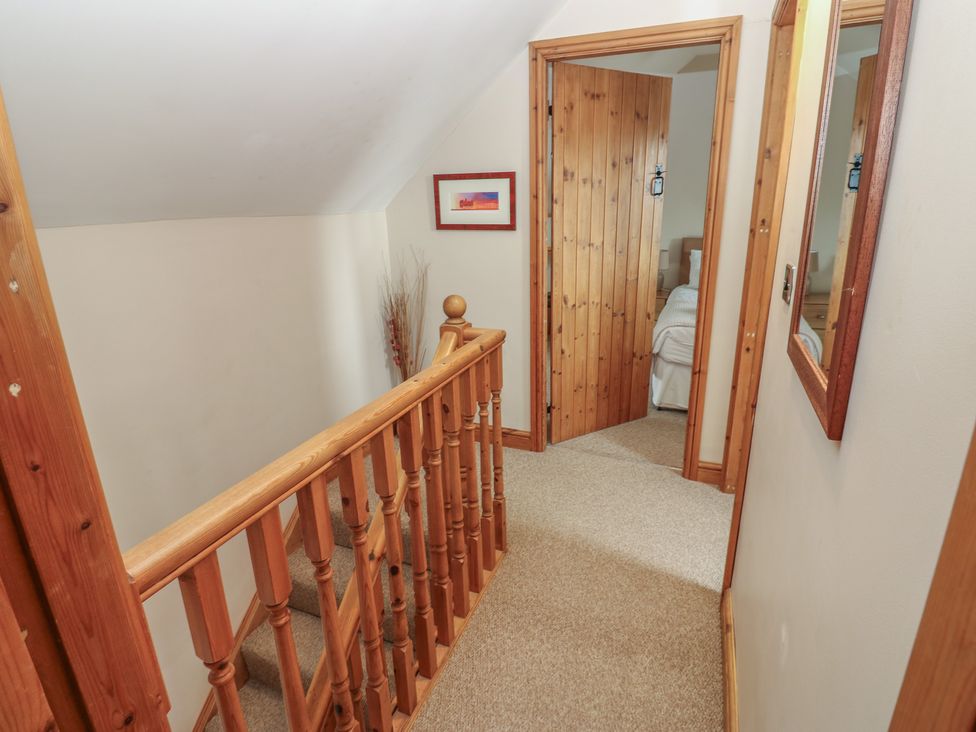 A hallway with a staircase and a mirror at Millstone Cottage in Ripon