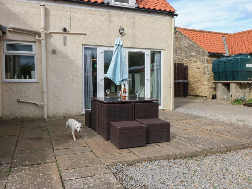 An outdoor seating area with a table and umbrella at Millstone Cottage Ripon