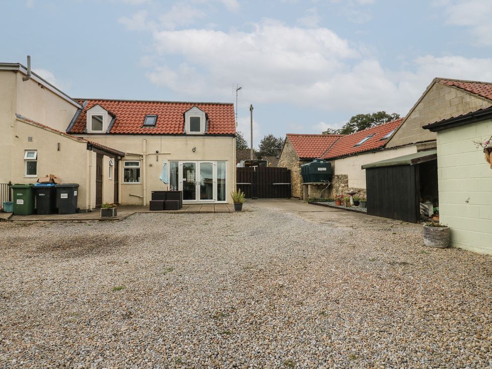An outdoor area with a house, gravel, and garbage bins at Millstone Cottage in Ripon