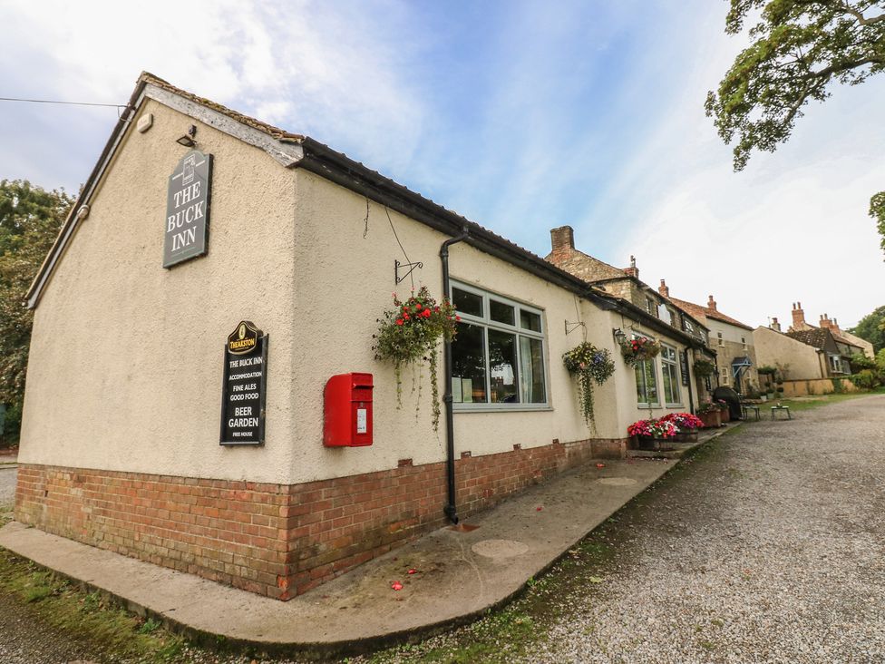 An exterior view of The Buck Inn with a sign and flower baskets in Ripon