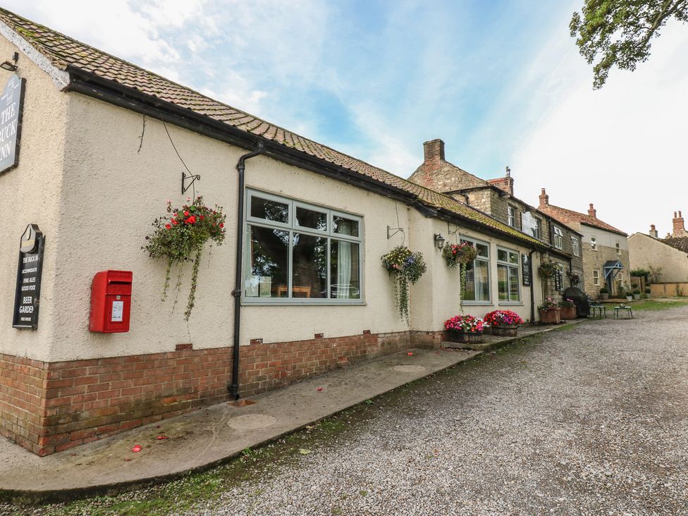 A pub with signage and flower planters at Millstone Cottage in Ripon
