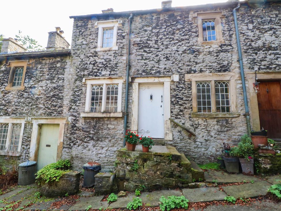 An outdoor view of a stone cottage with plants near the entrance at 73 Ravensdale Cottages, Cressbrook near Litton, Derbyshire