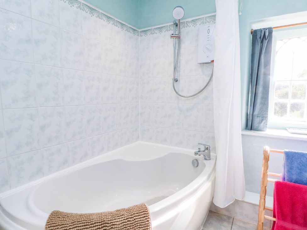 A bathroom with a bath tub and shower at 73 Ravensdale Cottages Cressbrook near Litton Derbyshire