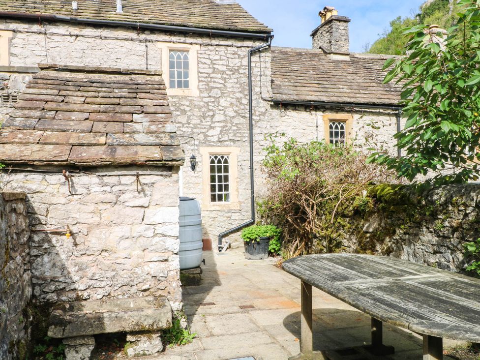An outdoor area with a wooden table and stone building at 73 Ravensdale Cottages Cressbrook near Litton Derbyshire