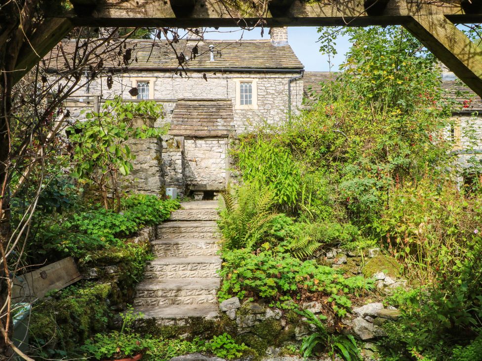 A garden with stone steps leading to a wall at 73 Ravensdale Cottages, Cressbrook near Litton, Derbyshire