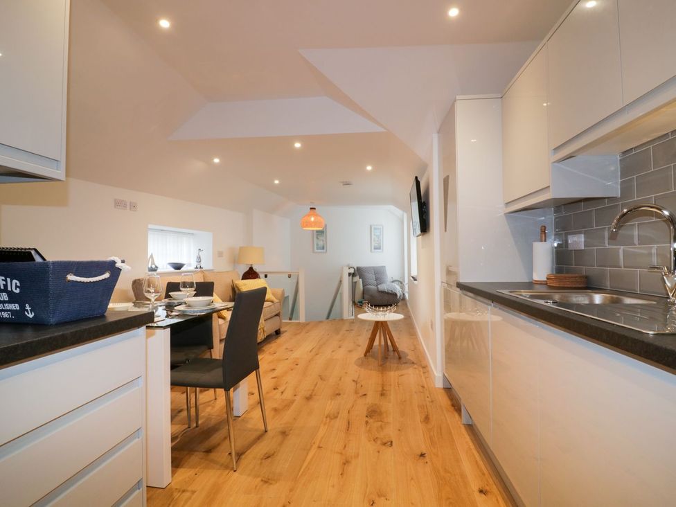 A kitchen area with dining table and seating at Fishermans Loft in Mevagissey