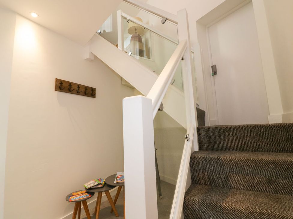 A staircase with a handrail and a door at Fishermans Loft in Mevagissey