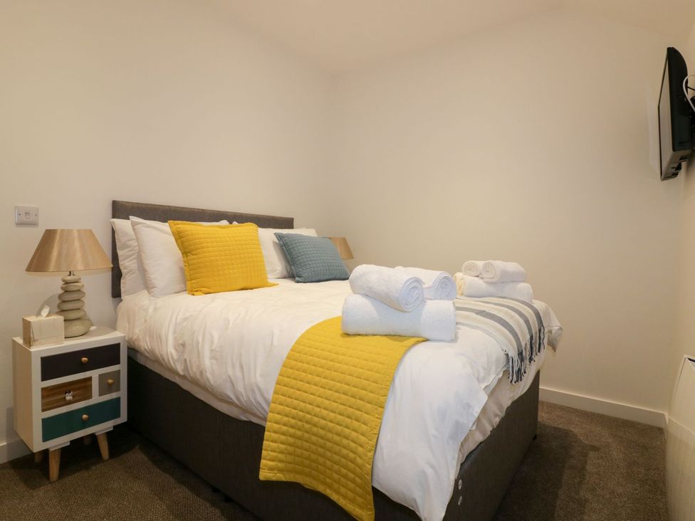 A bedroom with a bed a nightstand and a television at Fishermans Loft in Mevagissey