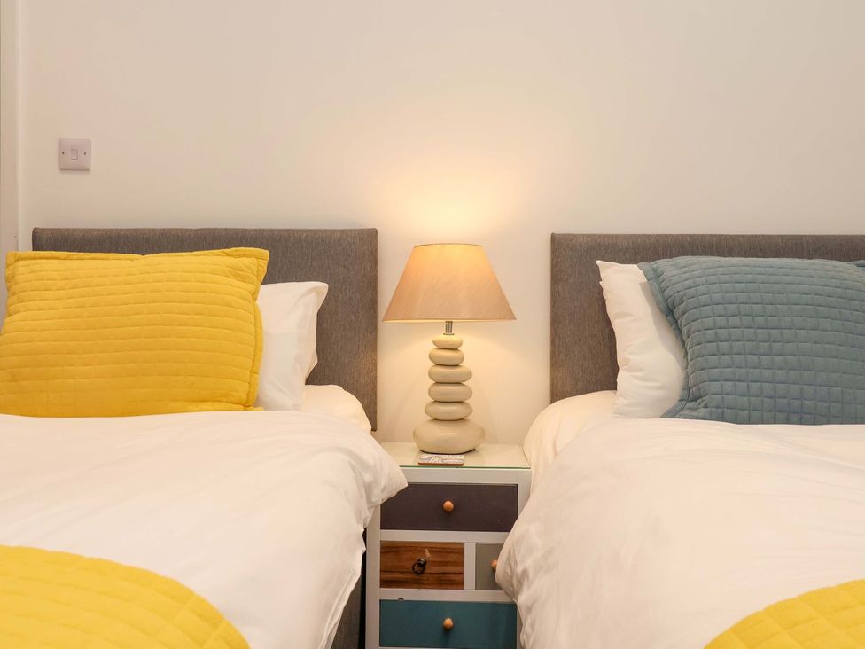 A bedroom with two beds and a lamp on a nightstand at Fishermans Loft in Mevagissey