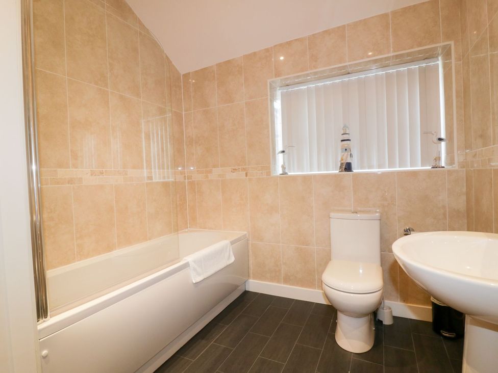 A bathroom with a bathtub, toilet, and sink at Fishermans Loft in Mevagissey